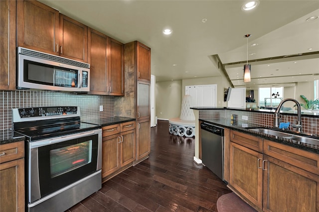 kitchen with backsplash, appliances with stainless steel finishes, dark hardwood / wood-style floors, sink, and decorative light fixtures