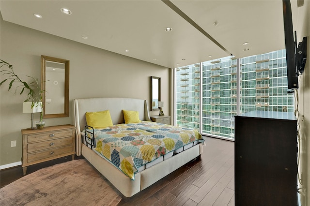 bedroom with a wall of windows and dark wood-type flooring