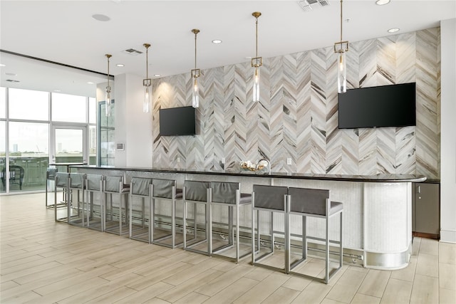 kitchen with light hardwood / wood-style flooring, a large island with sink, a breakfast bar area, and pendant lighting