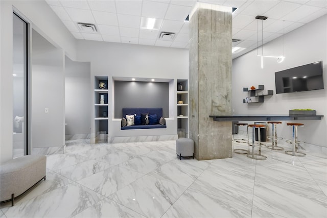 living room featuring a drop ceiling and built in features