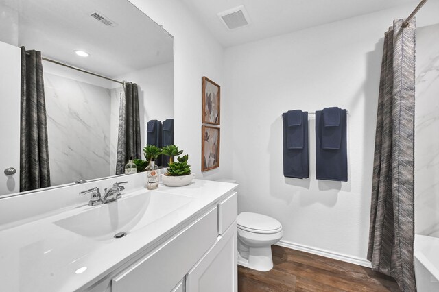 full bathroom featuring vanity, hardwood / wood-style floors, shower / tub combo, and toilet