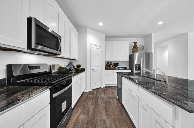 kitchen with sink, stainless steel appliances, dark hardwood / wood-style floors, white cabinets, and dark stone counters