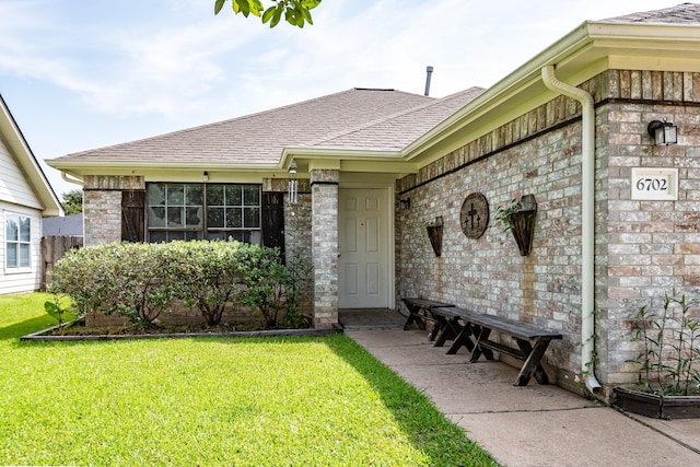 view of front of property with brick siding, a front lawn, and roof with shingles