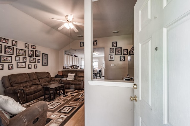 living area with a ceiling fan, lofted ceiling, visible vents, and wood finished floors