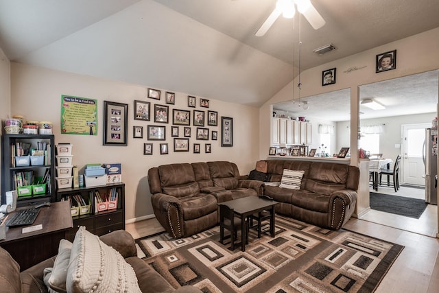 living room featuring lofted ceiling, visible vents, ceiling fan, and wood finished floors