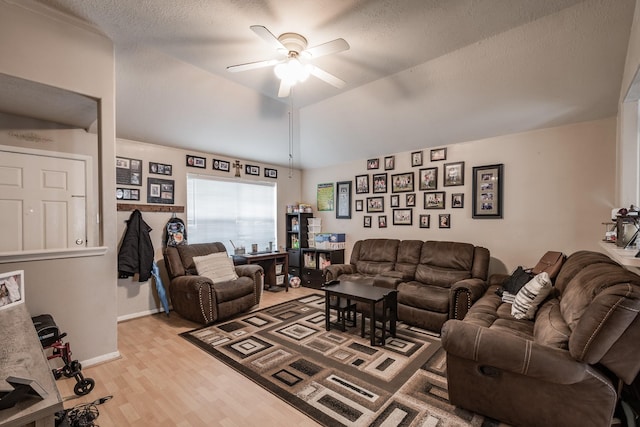 living room featuring lofted ceiling, light wood finished floors, ceiling fan, and a textured ceiling