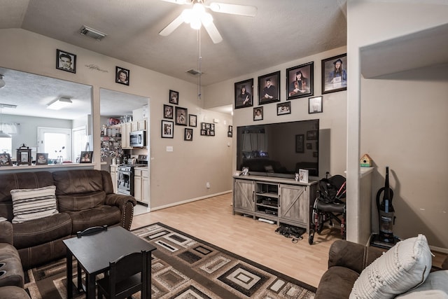 living area featuring light wood-style floors, bar, visible vents, and a ceiling fan