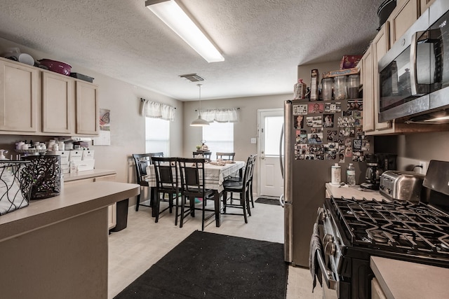 kitchen featuring pendant lighting, light floors, stainless steel appliances, light countertops, and visible vents