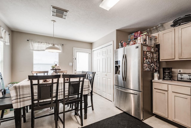 kitchen with a textured ceiling, visible vents, light countertops, hanging light fixtures, and stainless steel refrigerator with ice dispenser