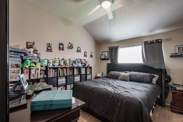 bedroom with light wood-style floors, a ceiling fan, vaulted ceiling, and a textured ceiling