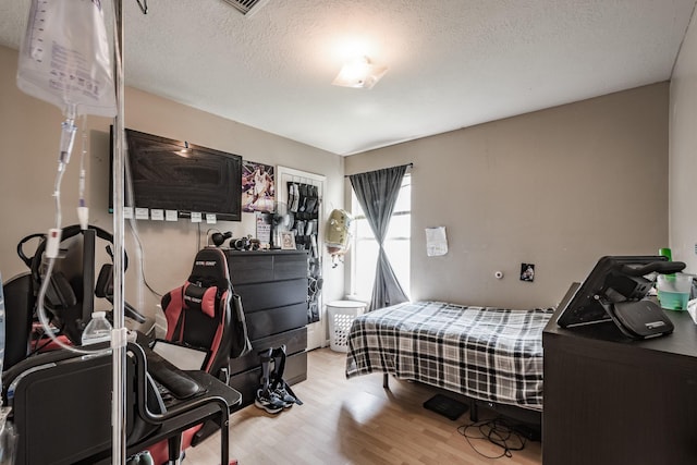 bedroom with a textured ceiling and wood finished floors