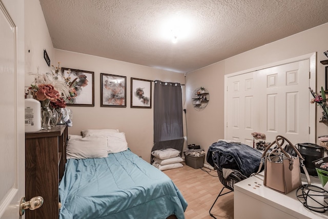 bedroom with a textured ceiling, a closet, and light wood-style flooring