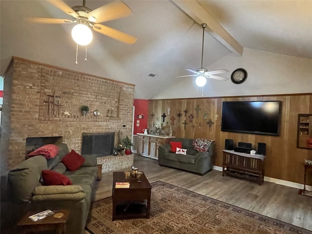 living room featuring vaulted ceiling with beams, wooden walls, hardwood / wood-style floors, a fireplace, and ceiling fan