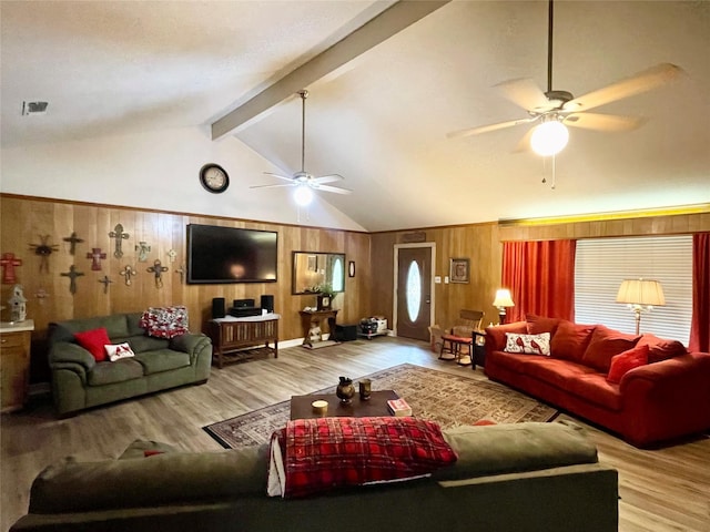 living room with ceiling fan, wooden walls, beamed ceiling, and light wood-type flooring