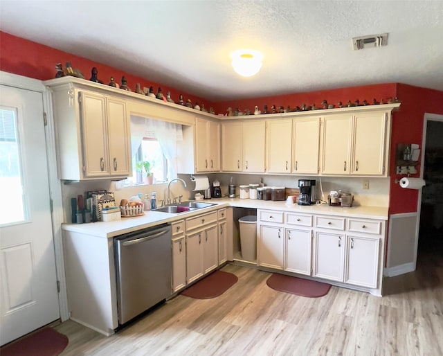 kitchen with stainless steel dishwasher, sink, a textured ceiling, and light wood-type flooring