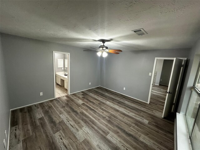 unfurnished bedroom with ensuite bath, a textured ceiling, ceiling fan, and wood-type flooring