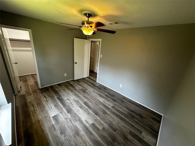 unfurnished bedroom featuring ceiling fan, a walk in closet, a closet, and hardwood / wood-style floors