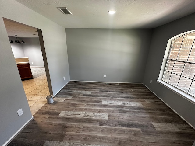 empty room featuring a textured ceiling and hardwood / wood-style flooring