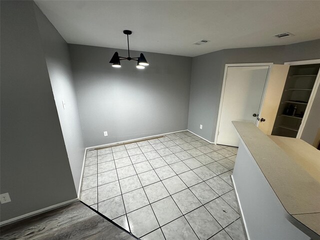 tiled spare room featuring a notable chandelier