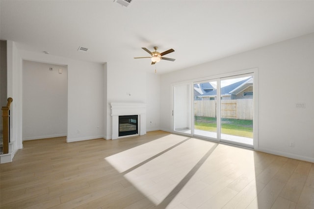 16006 Ruby Laurel Ct, Conroe, TX 77302 - unfurnished living room with a glass covered fireplace, light wood-type flooring, a ceiling fan, and baseboards