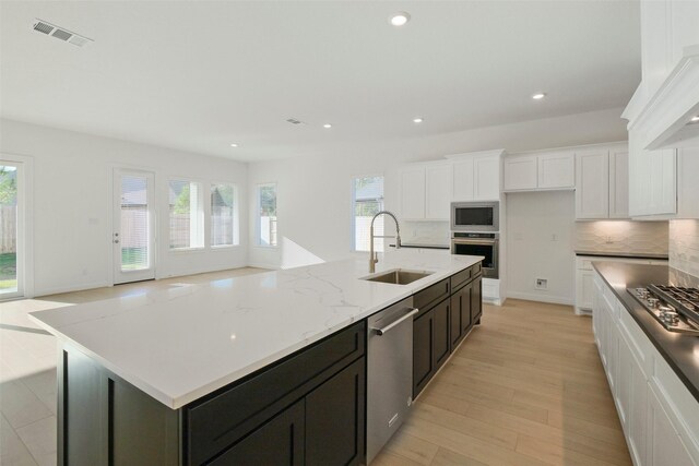 16006 Ruby Laurel Ct, Conroe, TX 77302 - kitchen with stainless steel appliances, a sink, white cabinetry, decorative backsplash, and recessed lighting