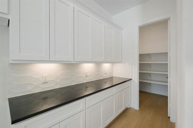 16006 Ruby Laurel Ct, Conroe, TX 77302 - kitchen featuring light wood-style flooring, white cabinetry, decorative backsplash, and dark countertops