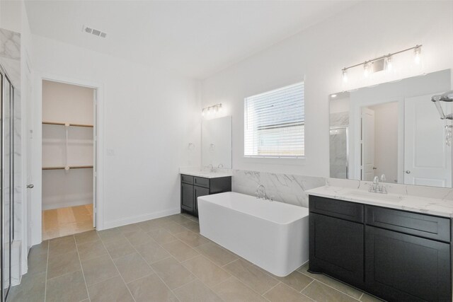 16006 Ruby Laurel Ct, Conroe, TX 77302 - full bath featuring a stall shower, two vanities, a freestanding bath, a spacious closet, and tile patterned flooring
