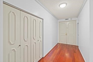 hall featuring hardwood / wood-style floors, crown molding, and a textured ceiling