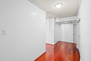 hallway with hardwood / wood-style floors and a textured ceiling