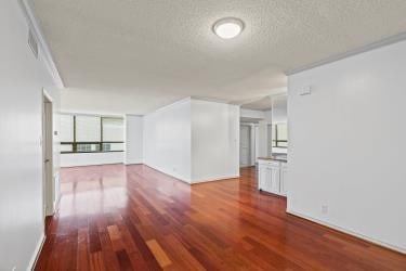 unfurnished living room with wood-type flooring and a textured ceiling