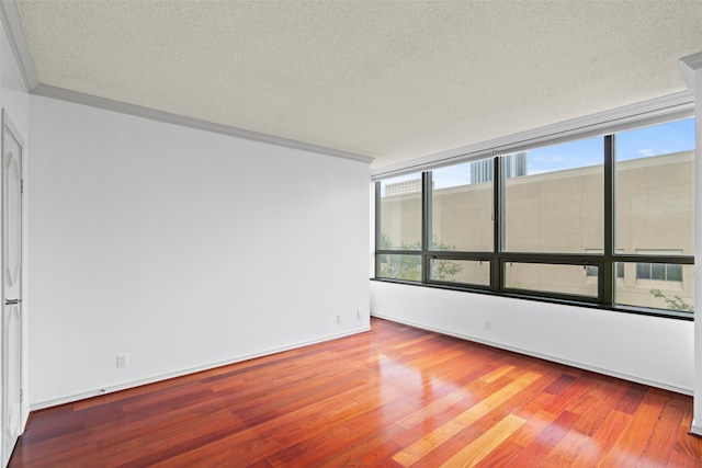 spare room featuring crown molding, light hardwood / wood-style flooring, and a textured ceiling