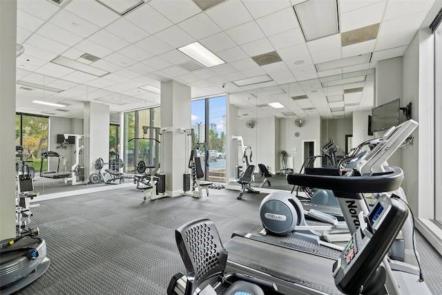 workout area with a paneled ceiling, plenty of natural light, and a wall of windows