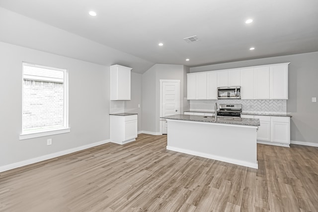 kitchen with backsplash, light wood-type flooring, a kitchen island with sink, white cabinetry, and stainless steel appliances