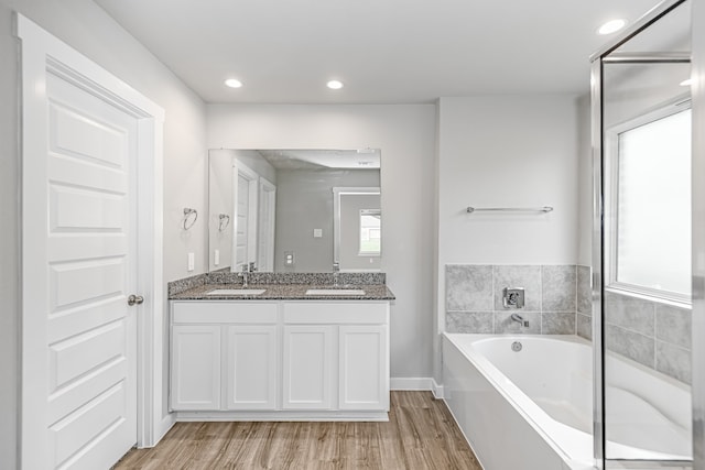 bathroom with hardwood / wood-style flooring, a tub, and vanity