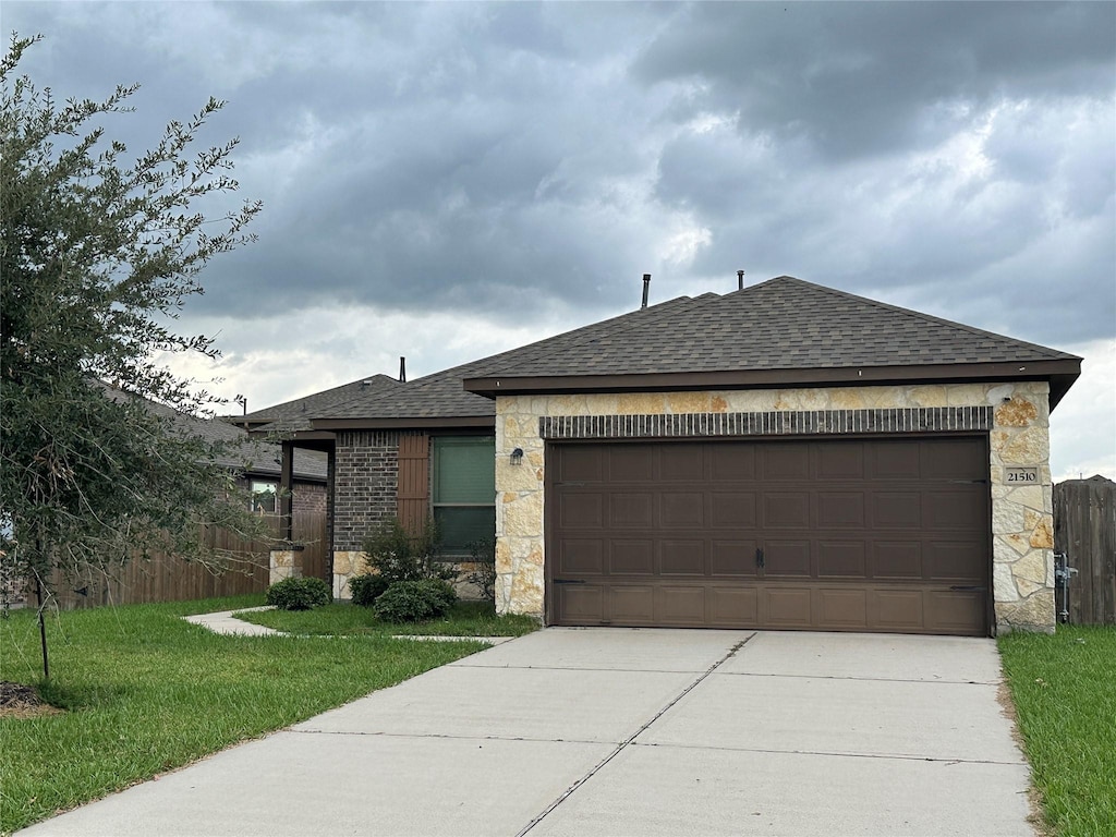 view of front of property featuring roof with shingles, concrete driveway, fence, a garage, and stone siding