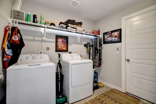 laundry area with wood-type flooring and washing machine and clothes dryer