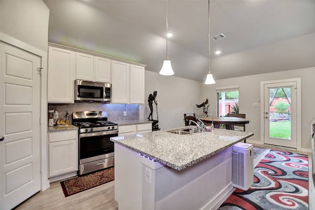 kitchen featuring a kitchen island with sink, sink, white cabinets, hanging light fixtures, and appliances with stainless steel finishes