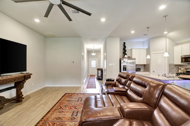 living room featuring ceiling fan, light hardwood / wood-style flooring, and vaulted ceiling