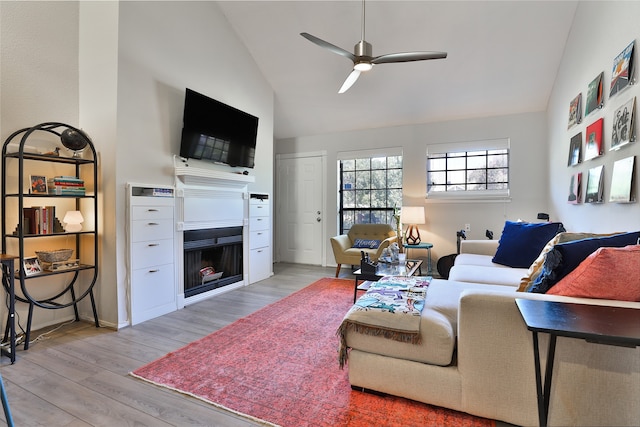 living room featuring ceiling fan, high vaulted ceiling, and light hardwood / wood-style flooring