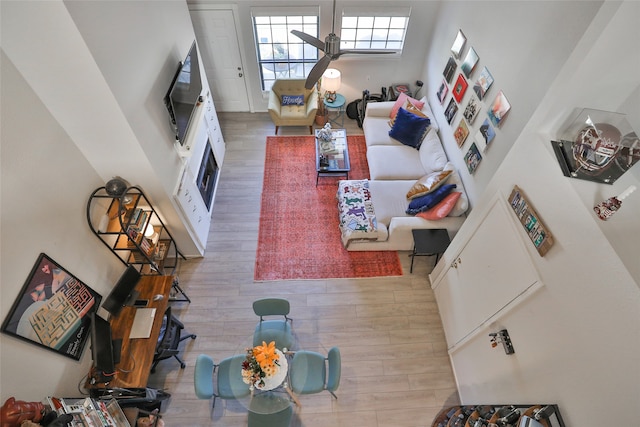 living room with hardwood / wood-style floors, ceiling fan, and a towering ceiling