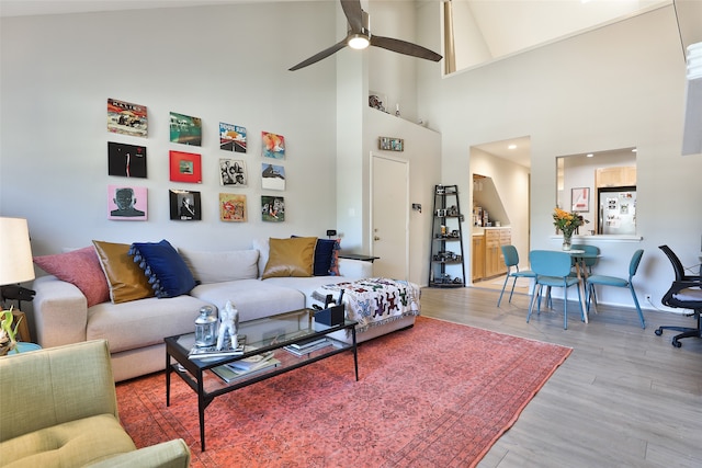 living room with ceiling fan, high vaulted ceiling, and light hardwood / wood-style floors