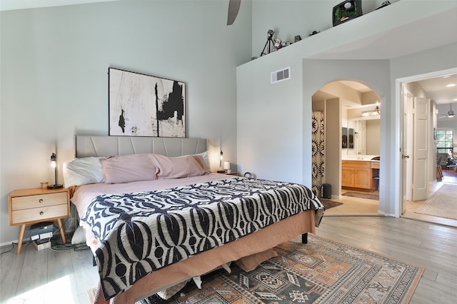 bedroom with ceiling fan, light wood-type flooring, and connected bathroom