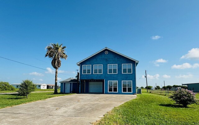 front of property featuring central air condition unit, a garage, and a front yard