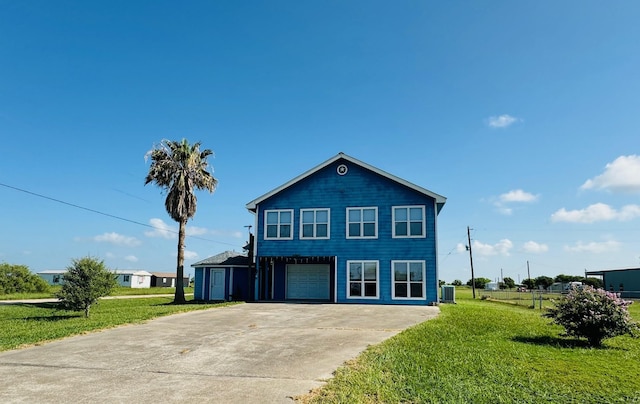 view of front of property featuring cooling unit, a garage, and a front yard