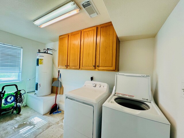 laundry room featuring water heater, cabinets, washer and clothes dryer, and light tile patterned floors