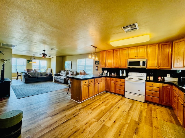 kitchen with white electric range, kitchen peninsula, light hardwood / wood-style floors, and a textured ceiling