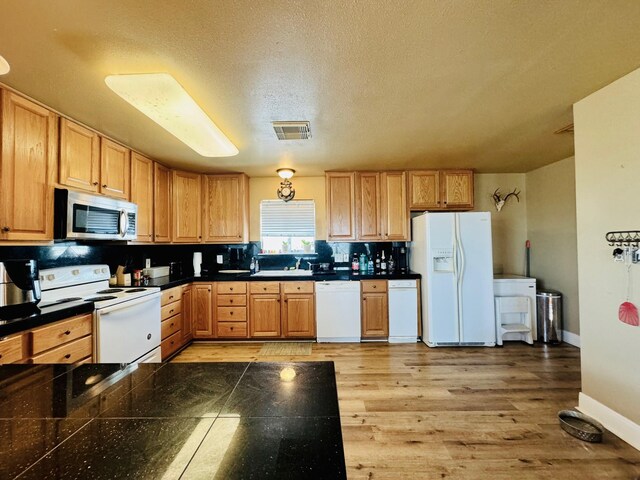 kitchen featuring tasteful backsplash, light wood-type flooring, white appliances, sink, and a textured ceiling