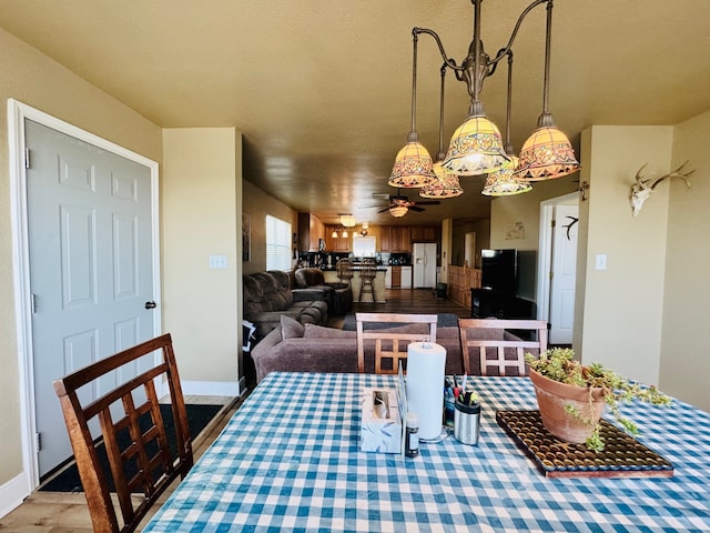 dining space with ceiling fan with notable chandelier and hardwood / wood-style floors