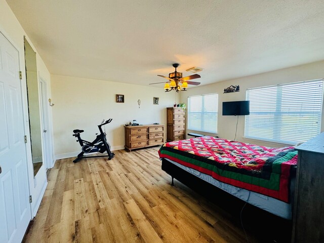 bedroom with a textured ceiling, ceiling fan, and hardwood / wood-style floors