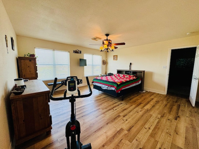 bedroom with a textured ceiling, wood-type flooring, and ceiling fan